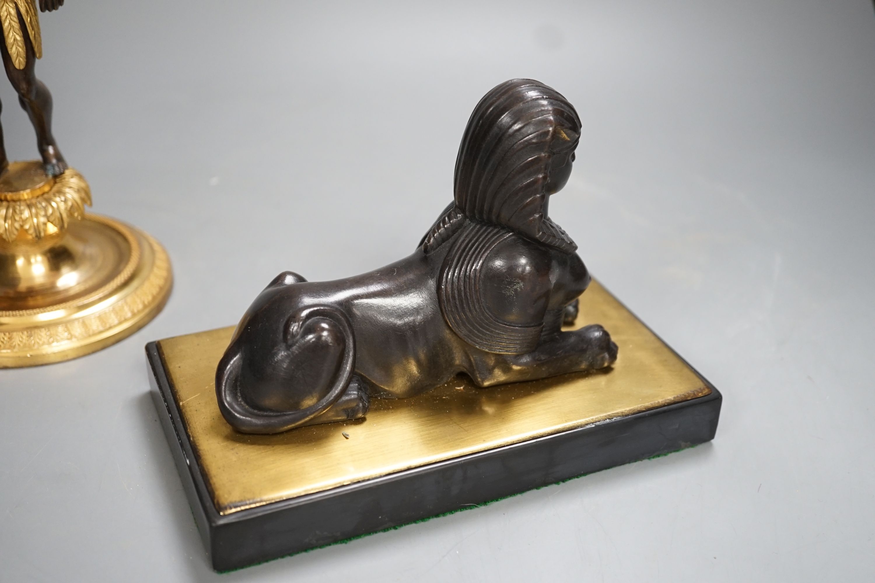 A patinated metal model of a sphinx and a bronze and gilt figure of a Nubian man. 22cm